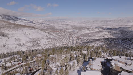 Beautiful-Aerial-Drone-Shot-Pulling-up-and-Pushing-over-Mountain-to-Reveal-Park-City,-Utah,-on-a-Sunny-Day-in-Winter,-4K