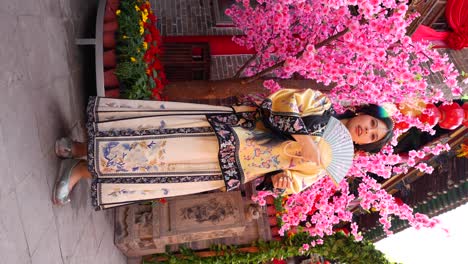 Qing-girl-in-Chinese-courtyard-in-front-of-cherry-blossom-tree-with-fan