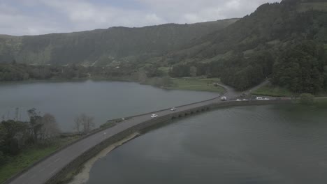 Un-Puente-Sobre-Un-Lago-Sereno-Rodeado-De-Exuberantes-Montañas-Verdes-En-Sete-Cidades,-Vista-Aérea