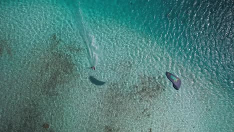 A-kitesurfer-gliding-over-crystal-clear-waters-near-a-tropical-island,-aerial-view