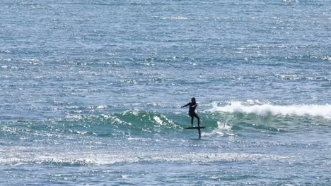 young-man-performing-a-perfect-carve-on-a-prone-foil-at-the-Guincho-surf-spot-in-Cascais