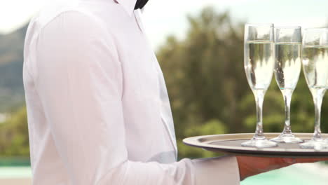 Smiling-waiter-holding-champagne-glasses