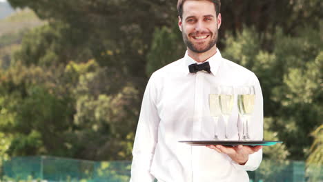 Smiling-waiter-holding-champagne-glasses