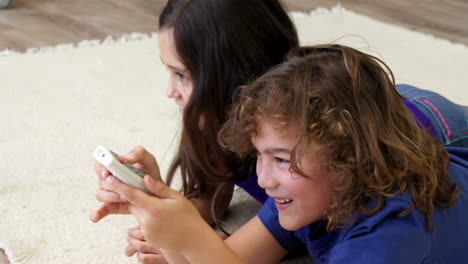 Brother-and-sister-lying-on-the-floor-using-remote-control