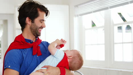 Happy-father-wearing-a-cape-and-holding-his-baby-with-a-cape-too