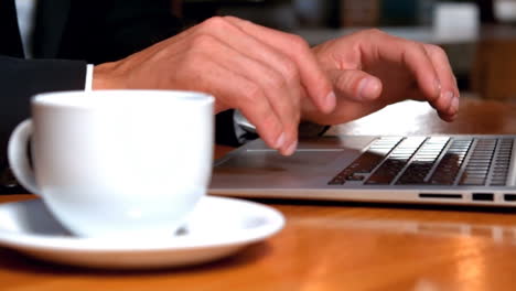 Businessman-working-on-laptop-while-drinking-coffee