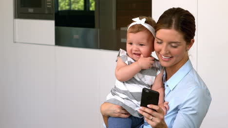 Madre-Sosteniendo-A-Su-Hija-Y-Usando-El-Teléfono