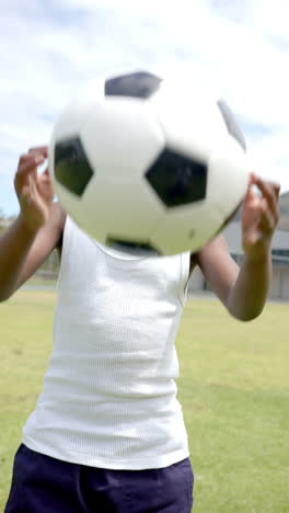 Vertical-video:-A-young-African-American-boy-balancing-soccer-ball-on-his-head