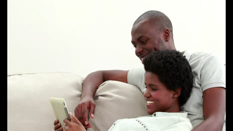Smiling-couple-using-tablet-on-the-couch