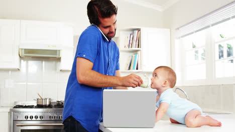 Father-calling-on-the-phone-and-taking-care-of-his-baby