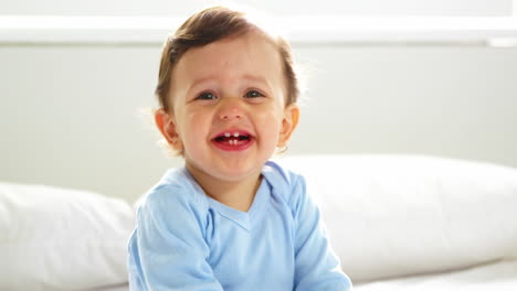 Lindo-Bebé-Con-Ropa-De-Dormir-Sonriendo-Y-Sentado-En-Una-Cama