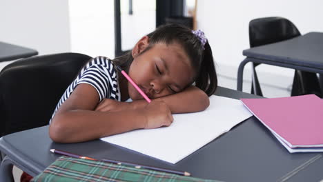 In-a-school-classroom,-a-young-biracial-girl-focuses-on-her-work