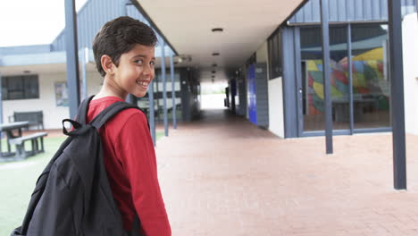 A-young-Caucasian-student-with-dark-hair-smiles-over-his-shoulder,-copy-space