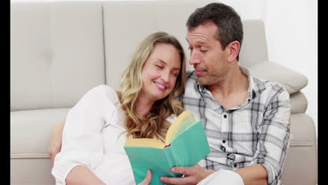 Husband-reading-book-with-his-pregnant-wife