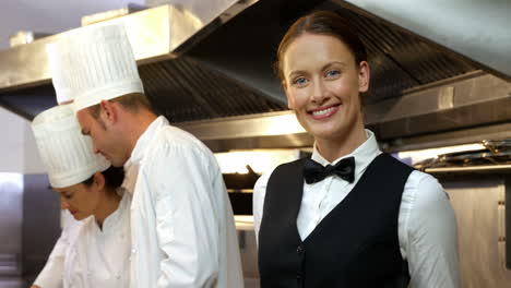 Group-of-chefs-putting-finishing-touch-and-giving-plate-to-the-waitress