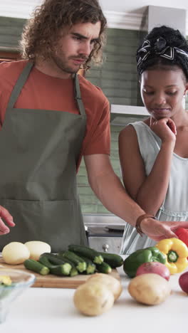 Vídeo-Vertical:-Pareja-Diversa-Preparando-Verduras-En-La-Cocina-De-Casa