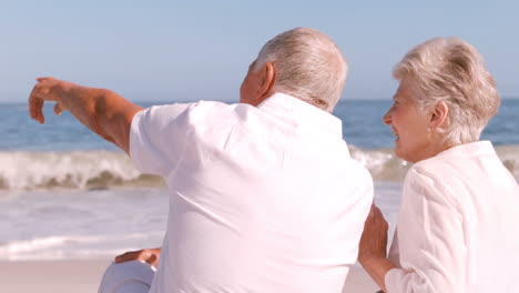 Mature-couple-sitting-on-the-beach-