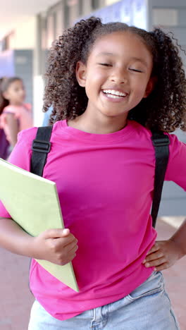 Vídeo-Vertical:-En-La-Escuela,-Una-Joven-Sosteniendo-Una-Carpeta-Se-Ríe