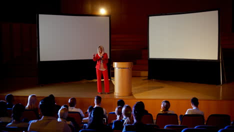 Mature-Caucasian-hijab-businesswoman-speaking-in-business-seminar-at-auditorium-4k