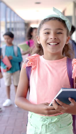 Vertical-video:-In-school,-young-girl-holding-a-book-is-smiling