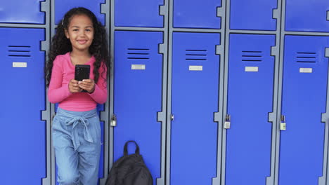 In-a-school-hallway,-a-young-biracial-girl-leans-against-blue-lockers-with-copy-space