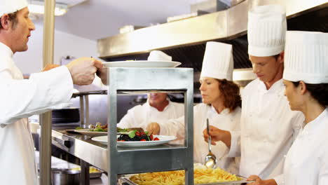 Group-of-chefs-giving-plates-on-order-line