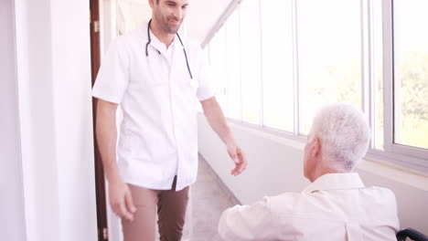 Male-doctor-assisting-senior-man-on-wheelchair