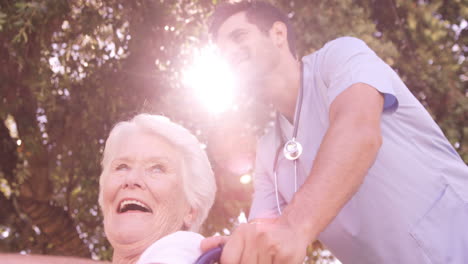 Male-doctor-assisting-senior-woman-on-wheelchair-in-the-backyard