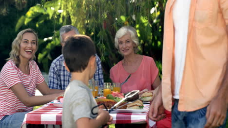 Familia-Feliz-Mirando-A-Un-Chico-Lindo-Preparando-La-Barbacoa