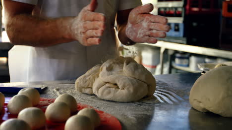 Chef-dusting-hands-with-flour-in-kitchen-4k