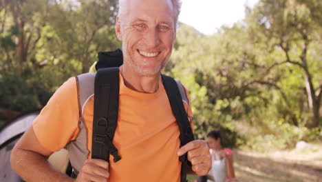 Portrait-of-man-carrying-a-backpack-at-campsite