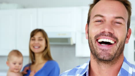 Portrait-of-happy-father-looking-his-wife-who-holding-their-baby