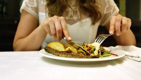 Pretty-girl-eating-a-fish-dish-in-restaurant