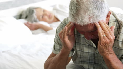 Alter-Mann-Mit-Kopfschmerzen-Sitzt-Auf-Dem-Bett