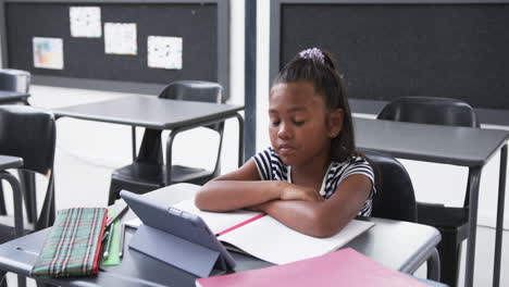 In-a-school-classroom,-a-young-African-American-girl-focuses-on-a-tablet