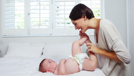 Happy-mother-playing-with-her-baby-on-a-bed