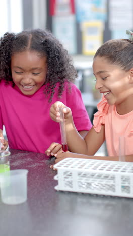 Vertical-video:-In-school,-two-girls-are-enjoying-chemistry-experiment