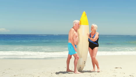 Senior-couple-holding-surfboard