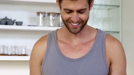 A-smiling-man-wearing-a-tank-top-using-his-digital-tablet
