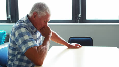 A-senior-man-sitting-at-table-thinking