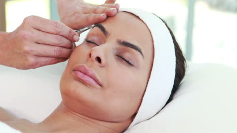 Woman-using-tweezers-on-patient-eyebrow