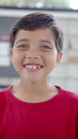 Vertical-video:-In-school,-young-biracial-boy-with-light-brown-skin-is-smiling