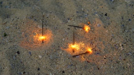 High-angle-view-of-sparklers-on-sand-at-beach-4k