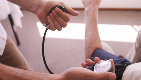 Male-doctor-checking-blood-pressure-of-senior-man