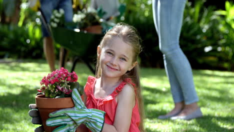 Porträt-Eines-Süßen-Mädchens,-Das-Einen-Blumentopf-Vor-Ihrer-Familie-Im-Garten-Hält