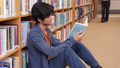Estudiante-Guapo-Leyendo-Un-Libro-Sentado-En-El-Suelo