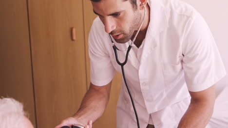 Male-doctor-checking-blood-pressure-of-senior-man