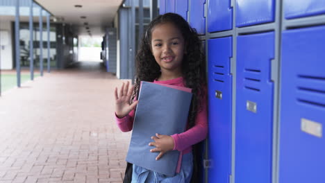 In-a-school-hallway,-a-young-biracial-girl-stands-by-blue-lockers-with-copy-space