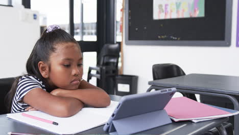 In-a-school-classroom,-a-young-African-American-girl-is-focused-on-a-tablet-with-copy-space