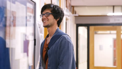 Student-checking-papers-hanging-in-the-hallway